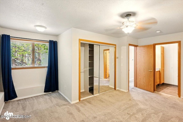 unfurnished bedroom with light colored carpet, a closet, a textured ceiling, and baseboards