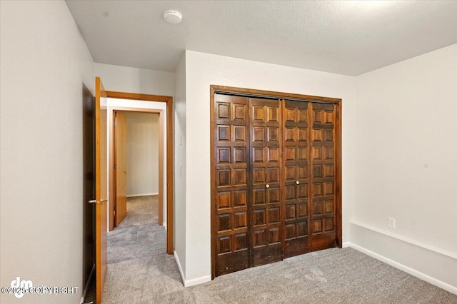 unfurnished bedroom with carpet, baseboards, and a closet