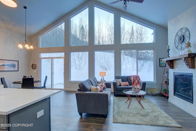 living room with plenty of natural light, dark hardwood / wood-style flooring, a high ceiling, and ceiling fan with notable chandelier