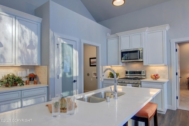 kitchen with appliances with stainless steel finishes, dark hardwood / wood-style flooring, sink, white cabinetry, and lofted ceiling