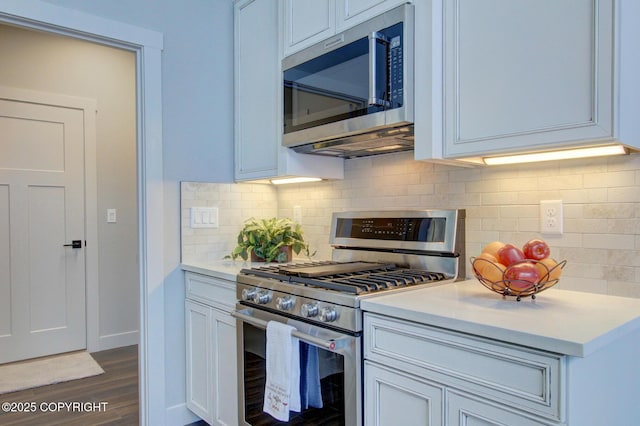 kitchen with dark hardwood / wood-style floors, decorative backsplash, and stainless steel appliances