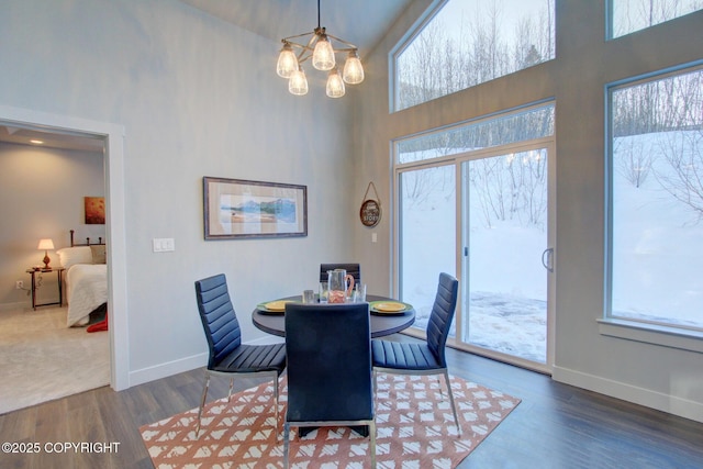 dining area with a towering ceiling, dark wood-type flooring, and a notable chandelier