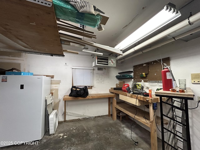 below grade area featuring freestanding refrigerator and a workshop area