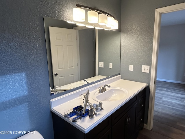 bathroom featuring vanity, wood finished floors, and a textured wall