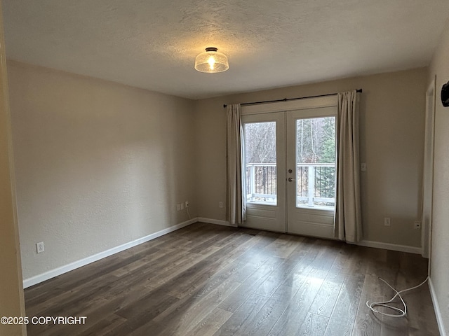 spare room featuring baseboards, dark wood finished floors, a textured ceiling, and french doors