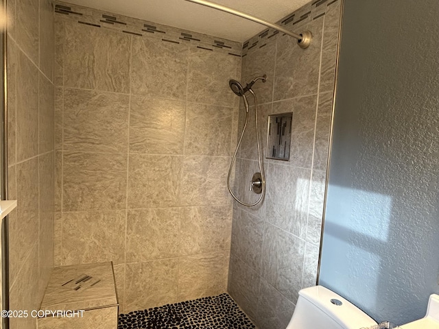 bathroom featuring a tile shower and toilet