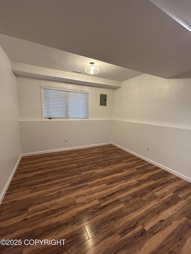 empty room with electric panel, dark wood finished floors, and baseboards