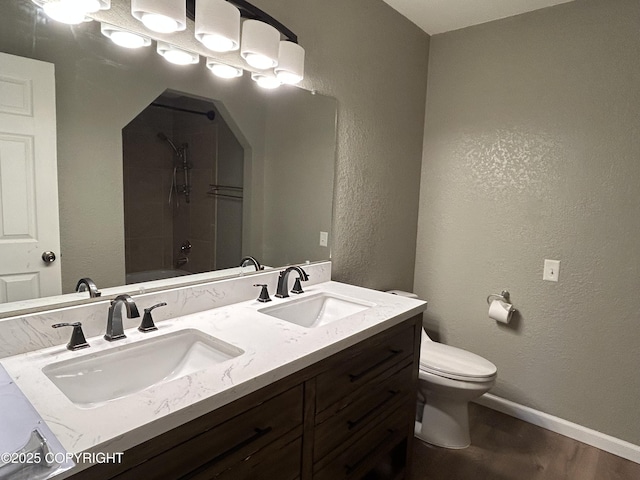 full bath with a textured wall, a sink, toilet, and baseboards