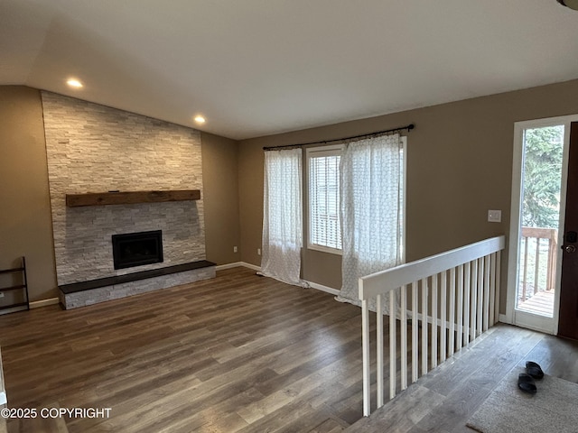 unfurnished living room featuring a fireplace, vaulted ceiling, baseboards, and wood finished floors