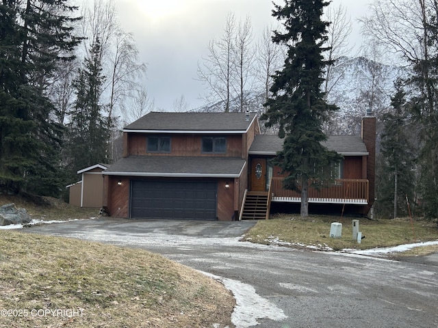 view of front of home with driveway, a chimney, and an attached garage