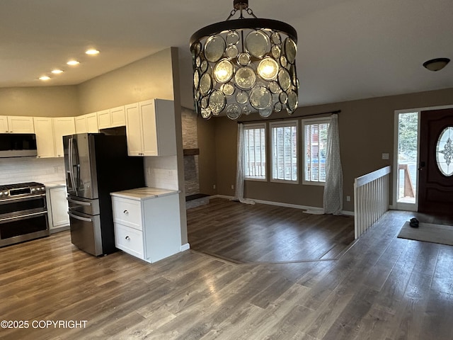 kitchen with stainless steel appliances, white cabinetry, light countertops, decorative backsplash, and an inviting chandelier