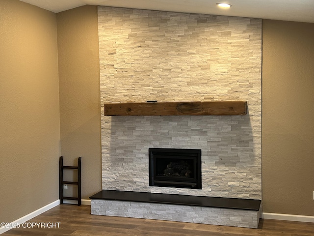 room details with a stone fireplace, wood finished floors, and baseboards