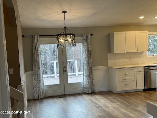 unfurnished dining area with a chandelier, wood finished floors, and french doors