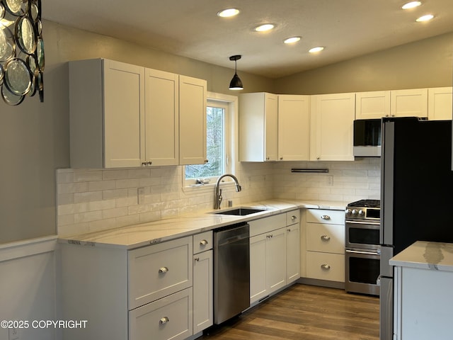 kitchen with light stone counters, dark wood-style floors, stainless steel appliances, white cabinetry, and a sink