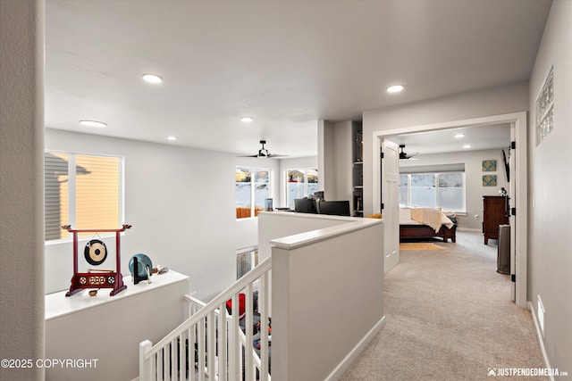 hall featuring a healthy amount of sunlight and light colored carpet