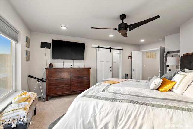 carpeted bedroom featuring ceiling fan and a barn door