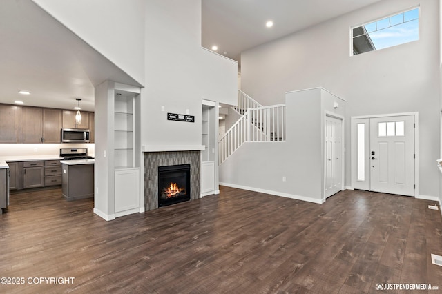 unfurnished living room featuring dark hardwood / wood-style flooring, built in features, and a high ceiling