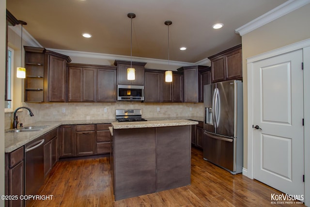 kitchen featuring sink, light stone countertops, decorative light fixtures, dark brown cabinetry, and stainless steel appliances