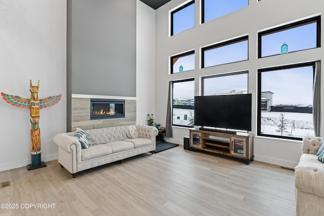 living room featuring a tiled fireplace and light wood-type flooring