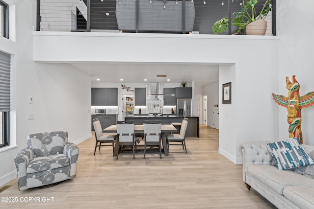 dining room featuring light hardwood / wood-style flooring, a towering ceiling, and sink