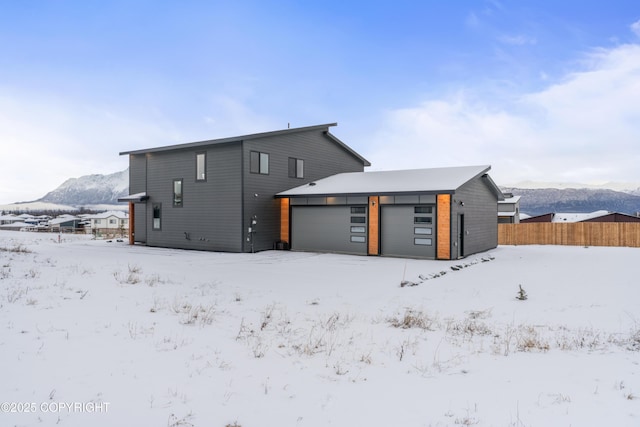 snow covered house with a mountain view and a garage