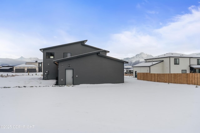 snow covered back of property featuring a mountain view