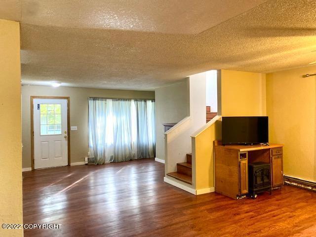 unfurnished living room featuring hardwood / wood-style floors and a textured ceiling