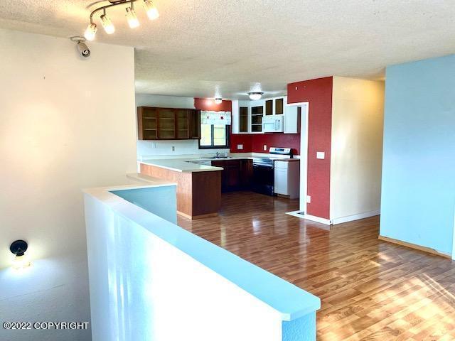 kitchen featuring electric range, kitchen peninsula, hardwood / wood-style floors, and a textured ceiling