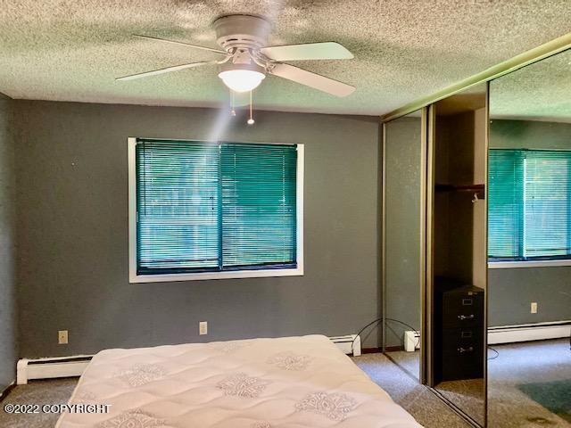 unfurnished bedroom with ceiling fan, a closet, carpet floors, and a baseboard radiator