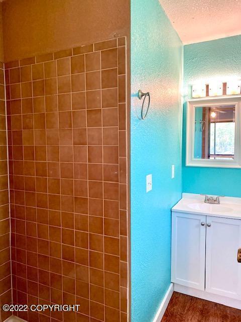 bathroom featuring vanity, a shower, a textured ceiling, and hardwood / wood-style floors