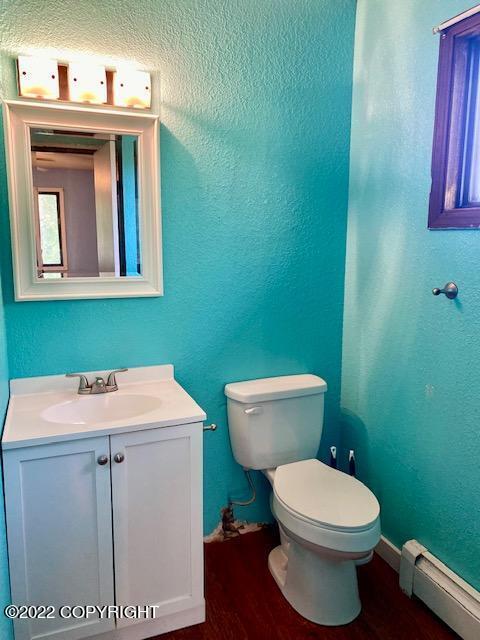 bathroom featuring hardwood / wood-style flooring, toilet, vanity, and a baseboard heating unit