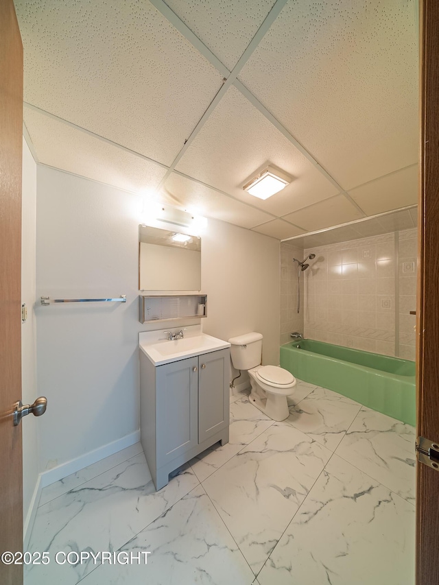 full bathroom featuring vanity, a paneled ceiling, tiled shower / bath combo, and toilet