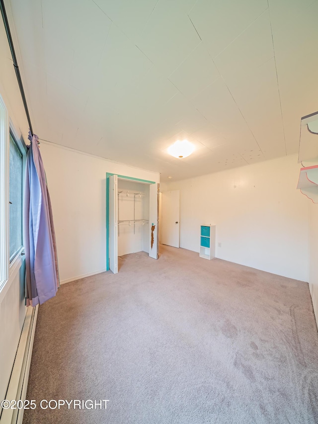 carpeted empty room featuring a baseboard heating unit