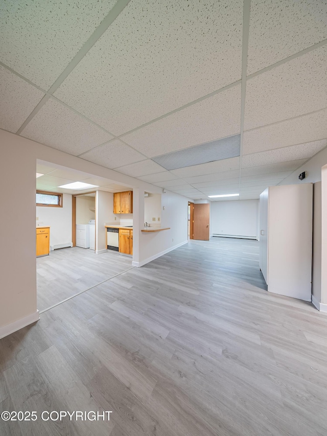 basement featuring a drop ceiling, light hardwood / wood-style floors, washer / dryer, and a baseboard radiator