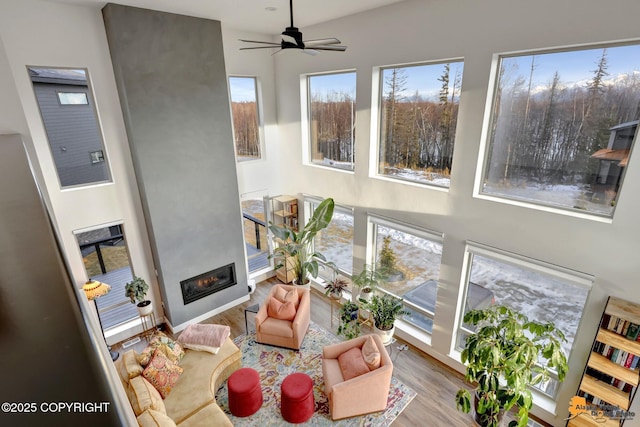 sunroom featuring ceiling fan and a fireplace