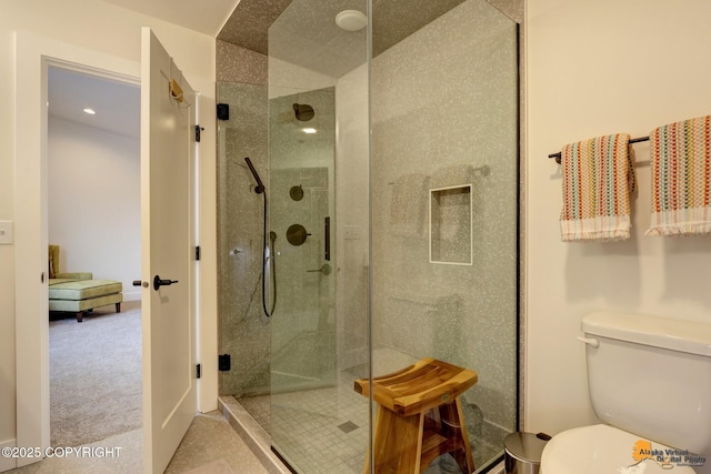 bathroom featuring toilet and a shower with door