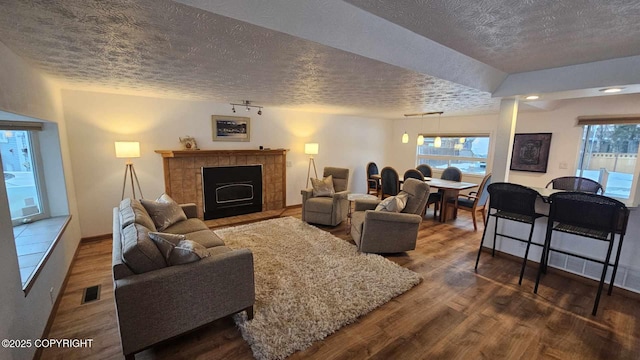 living room with a fireplace, a textured ceiling, and hardwood / wood-style flooring