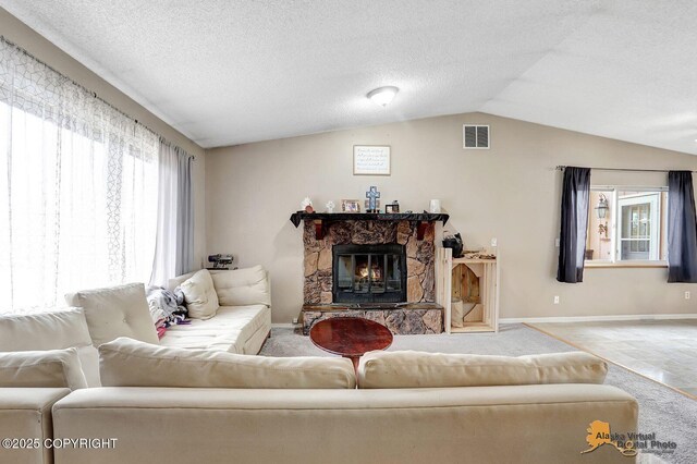 5450 E Alder Dr, Wasilla, AK 99654 - carpeted living room with a textured ceiling, visible vents, a stone fireplace, baseboards, and lofted ceiling