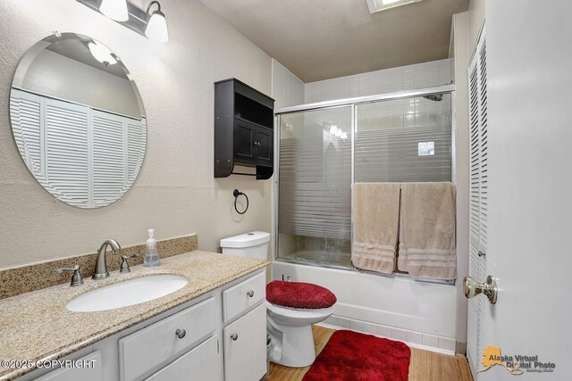 5450 E Alder Dr, Wasilla, AK 99654 - full bath featuring a textured wall, vanity, toilet, combined bath / shower with glass door, and wood finished floors