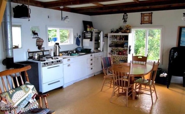 kitchen with white cabinets, white gas stove, plenty of natural light, and sink