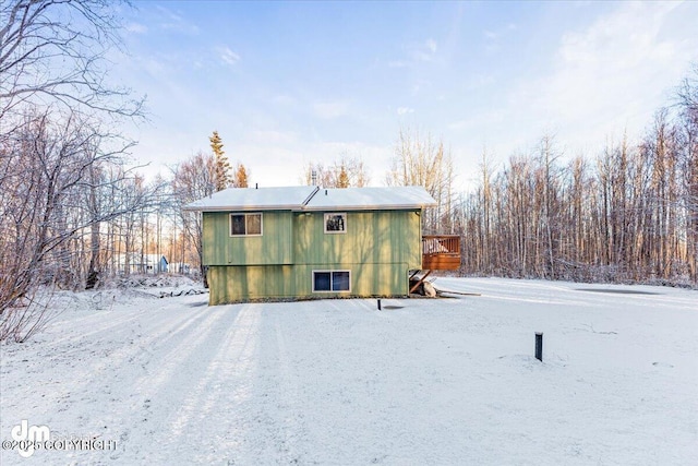 snow covered back of property with a wooden deck