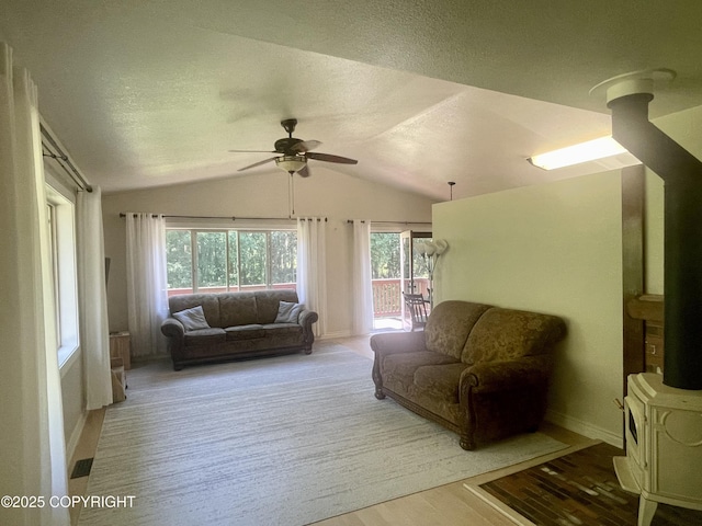 living room with a textured ceiling, vaulted ceiling, light hardwood / wood-style floors, and ceiling fan