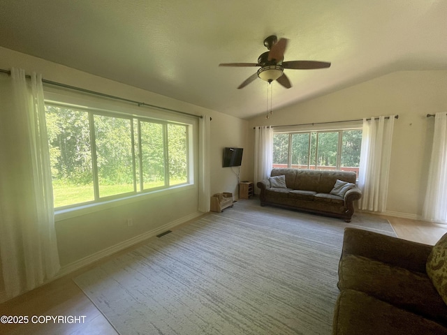 carpeted living room with ceiling fan, vaulted ceiling, and a wealth of natural light