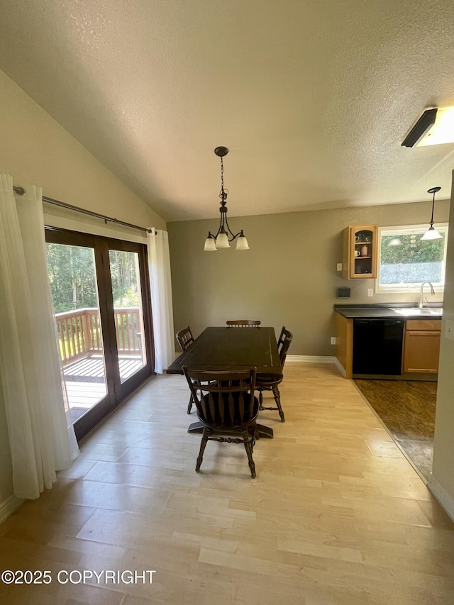 dining space with lofted ceiling, sink, a wealth of natural light, and light wood-type flooring