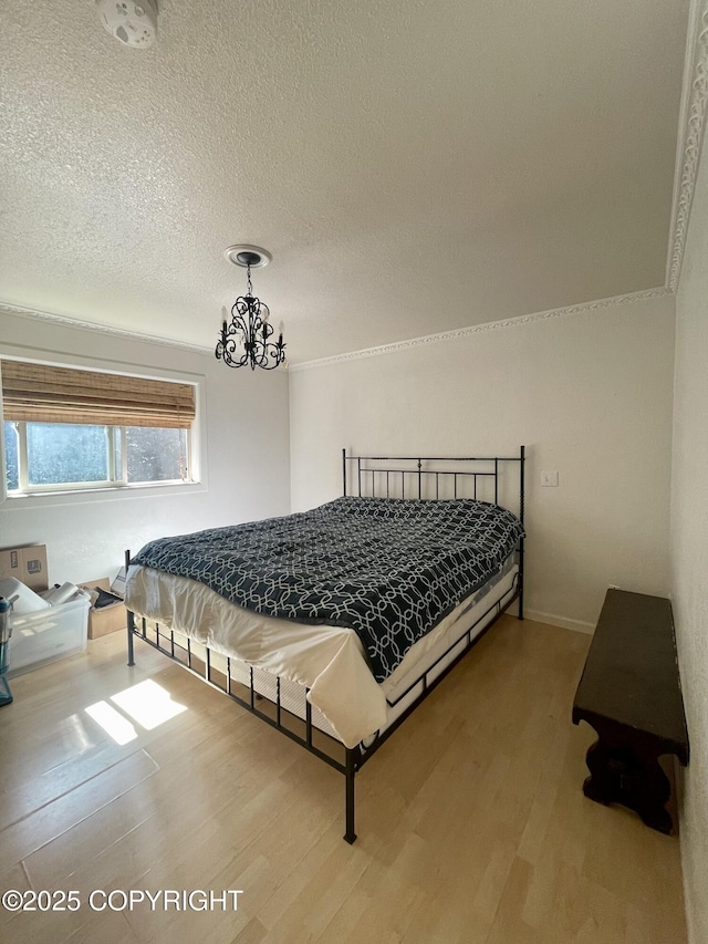 bedroom with hardwood / wood-style flooring, crown molding, an inviting chandelier, and a textured ceiling