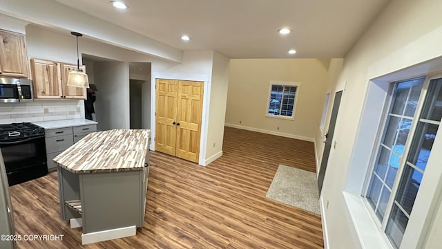 kitchen with gas stove, a kitchen island, decorative light fixtures, dark hardwood / wood-style flooring, and tasteful backsplash