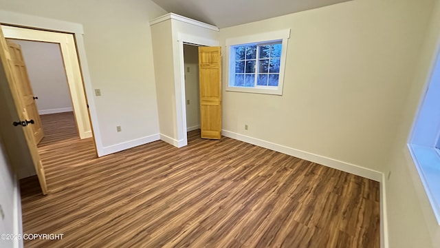 unfurnished bedroom featuring lofted ceiling, a closet, and hardwood / wood-style floors