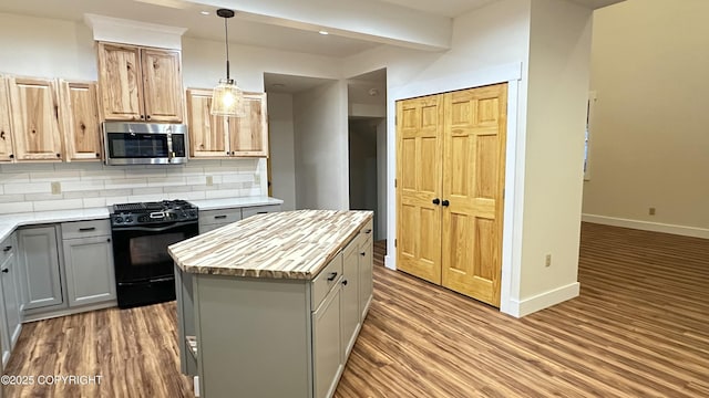 kitchen featuring a center island, decorative light fixtures, backsplash, black range with gas cooktop, and gray cabinetry