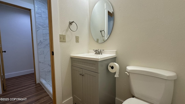 bathroom featuring hardwood / wood-style floors, toilet, vanity, and walk in shower