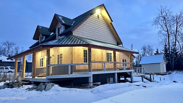 snow covered property with a storage shed and a deck